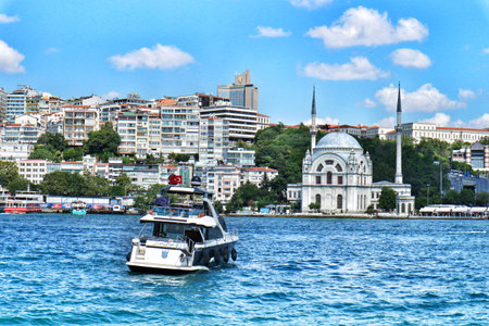 Istanbul, Turkey on 12 July 2022. A boat is sailing on water in front of a cityscape with buildings under a blue sky, creating a scenic view ideal for travel and urban landscape designs.のeditorial素材