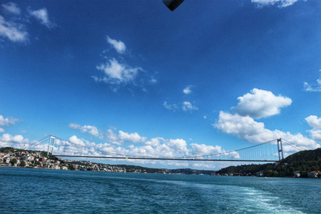 Istanbul, Turkey on 12 July 2022. A long bridge spans across a wide body of water under a bright blue sky with fluffy clouds, connecting two distinct land masses visible on either side Great for travel and nature themes.のeditorial素材