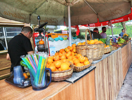 Istanbul, Turkey on 12 July 2022. Person making juice at an outdoor stand with oranges, pineapples, and other fruits displayed in baskets A vibrant scene suitable for food or travel content.のeditorial素材
