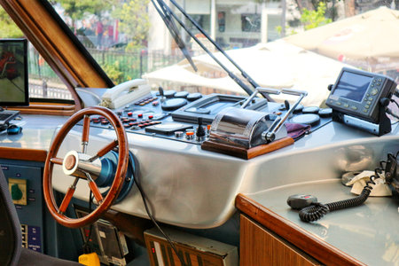 Istanbul, Turkey on 12 July 2022. Interior view of a boat featuring a wooden steering wheel, control panel, and various electronic devices Use this image for boating or nautical themes.のeditorial素材