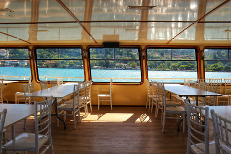 Istanbul, Turkey on 12 July 2022. Inside a boat, tables and chairs are arranged with a scenic view of the sea and coastline creating a tranquil setting, ideal for events or scenic dining cruises.のeditorial素材
