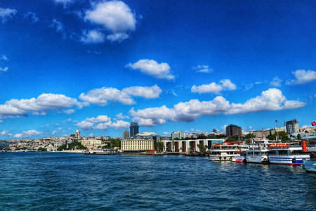 Istanbul, Turkey on 12 July 2022. Boats are docked at a city harbor under a bright blue sky with scattered clouds providing a peaceful view and a scenic travel background.のeditorial素材