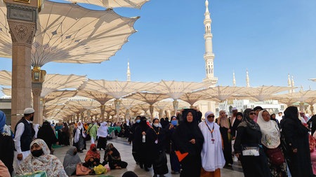 Madinah, Saudi Arabia on 29 February 2024. People are walking beneath large sunshade umbrellas...