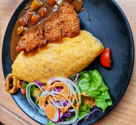 This savory Japanese omurice with tonkatsu and curry is presented on a plate with fresh salad; use...