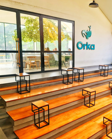 Jakarta, Indonesia on 1 Jun 2025. Tiered wooden seating with black frame tables offers a unique layout in a cafe, with natural light streaming through the large windows Perfect for architectural or interior design concepts.のeditorial素材