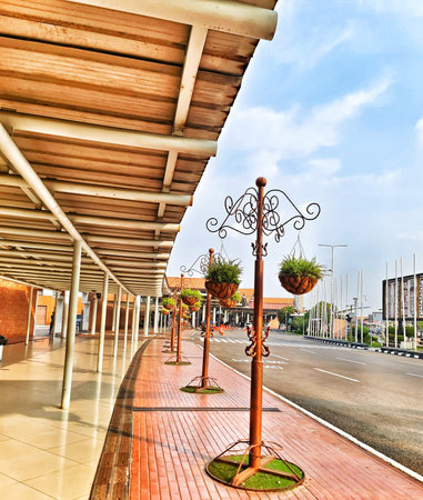 Cengkareng, Indonesia on 28 Sep 2024. A long walkway under a covered area at an airport features a row of decorative metal stands each holding hanging planters with lush greenery. The scene is bright and peaceful, showcasing a pleasing architectural detaiのeditorial素材