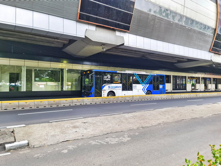 Jakarta, Indonesia on 20 Sep 2024. A blue and white Jak Lingko bus is parked under a modern city...