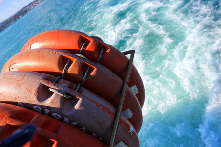 Istanbul, Turkey on 12 July 2022. Bosphorus. Stacked orange life preservers secured on the back of a boat create a nautical scene, with turquoise water churning behind the vessel providing a dynamic sense of travel, suitable for tourism or safety campaigns.の写真素材