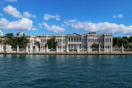 Istanbul, Turkey on 12 July 2022. Grand building stands along the waterfront under a bright blue sky with puffy white clouds, creating a tranquil and scenic view ideal for travel or architectural projects.のeditorial素材