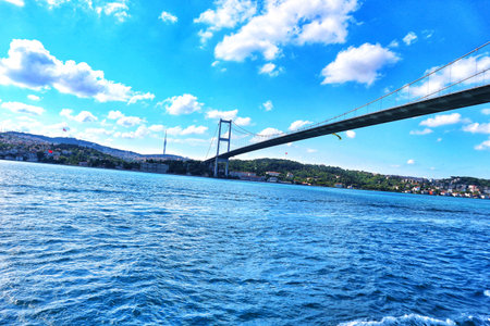 Istanbul, Turkey on 12 July 2022. Vibrant blue water ripples below a massive suspension bridge under a sunny sky with scattered clouds, offering a tranquil travel scene Perfect for showcasing infrastructure or travel.のeditorial素材