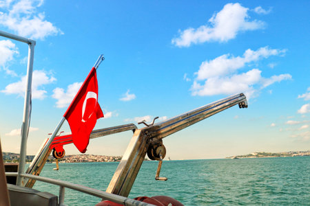 Istanbul, Turkey on 12 July 2022. Bosphorus. View of the blue sea and cloudy sky from a boat, featuring a red flag on a sunny day Perfect for travel and vacation content.のeditorial素材