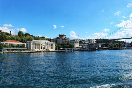 Istanbul, Turkey on 12 July 2022. Bosphorus. A serene river scene shows architecture, including a building with prominent columns and a bridge in the distance, under a clear sky Ideal for travel or cityscape content.のeditorial素材