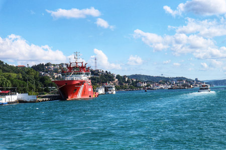 Istanbul, Turkey on 12 July 2022. Red boat is docking near a city coast with a bright blue sky above on a sunny day, perfect for travel-related content.のeditorial素材