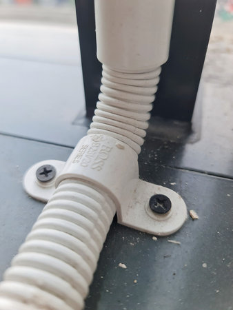 Jakarta, Indonesia on 26 September 2025. A white corrugated pipe is fastened to a dark gray surface with screws, suggesting an industrial or construction setting, ideal for utility or repair-related content.のeditorial素材