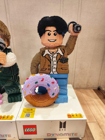 Odaiba, Japan on 14 October 2025. Smiling brick figure holds camera aloft above a glazed donut with sprinkles, the scene brightly lit on a display stand, suggesting a fun, creative build for toy and hobby-related promotions.のeditorial素材
