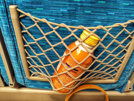 Osaka, Japan on 18 Oct 2025 Orange bottle is secured in netting on a teal seat Travel is shown and could depict the simple pleasures of a drink on the go.のeditorial素材