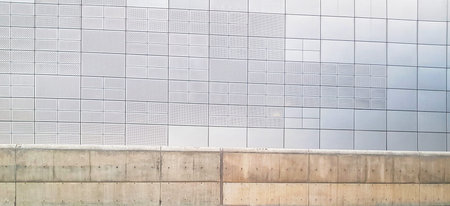 Abstract textured gray metal wall is separated by a concrete barrier in a modern minimalist style...