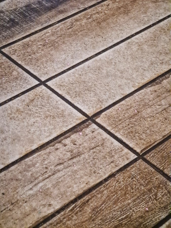 Brown and tan wood-like tile flooring creates a rustic and textured surface with dark grout lines,...