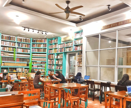 Jakarta, Indonesia on 30 May 2025. People are reading and working on laptops at wooden tables in a...