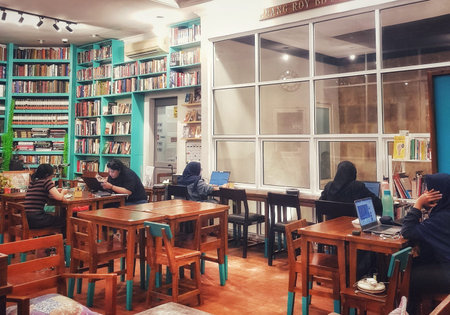 Jakarta, Indonesia on 30 May 2025. Several people are studying with laptops at wooden tables in a...