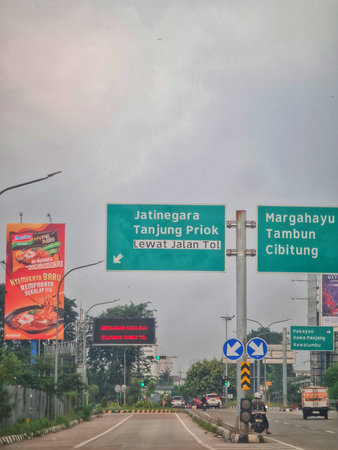 Bekasi, Indonesia on 4 July 2025. Road with green highway signs and traffic flows through an urban...