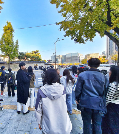 Seoul, South Korea on 10 Nov 2024. A group walks along a city sidewalk lined with trees showing fall...