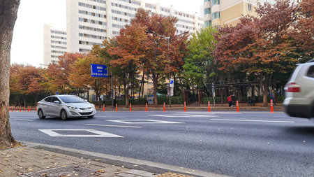 Seoul, South Korea on 10 Nov 2024. Silver car traveling on a black paved road in a city neighborhood...