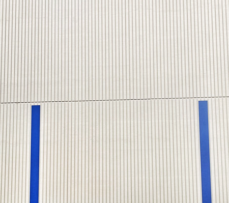 Close-up of a wall featuring a vertical striated pattern and blue vertical stripes This minimalistic...