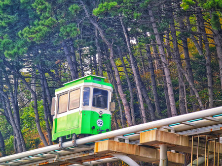 Busan, South Korea on 9 Nov 2024. A green and white automated transit car moves along an elevated...