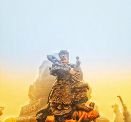 Sa Pa, Vietnam on 15 May 2025. Fansipan. Bronze statue stands playing a stringed instrument, featuring detailed patterns and wearing a crown, set against a hazy golden background evoking a mystical and cultural atmosphere suitable for travel or cultural pのeditorial素材