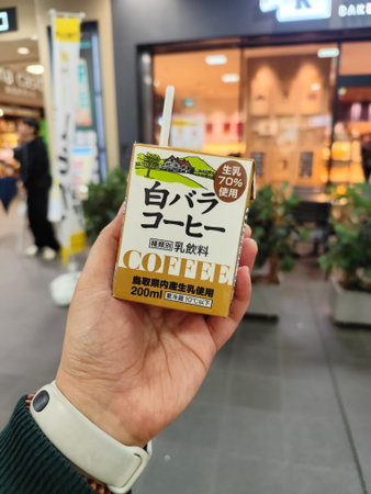Shibuya, Japan on 19 Oct 2025. A person holding a Japanese coffee milk carton with a straw in a busy...