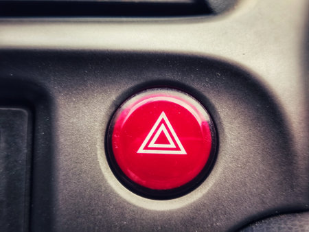 Close up of a red hazard warning triangle button on a car dashboard, signaling emergency or alert...