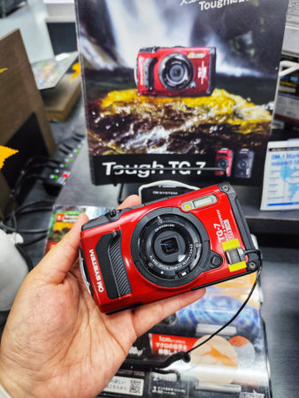 Osaka, Japan on 18 Oct 2025. Person holds a red compact camera in a store display with product...