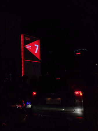 Jakarta, Indonesia on 1 Nov 2025. Dark night scene showing a red illuminated entrance sign and rear...