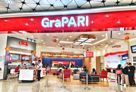 Jakarta, Indonesia on 8 Feb 2025. Inside a brightly lit GraPARI store, customers receive mobile and...
