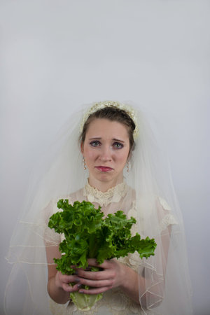 Pretty young bride holds lettuce in place of bouquet