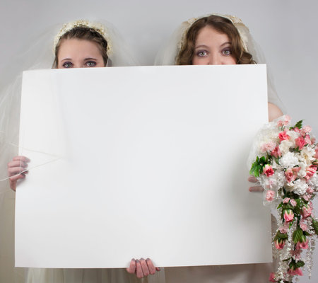 Two young brides holding blank signの写真素材