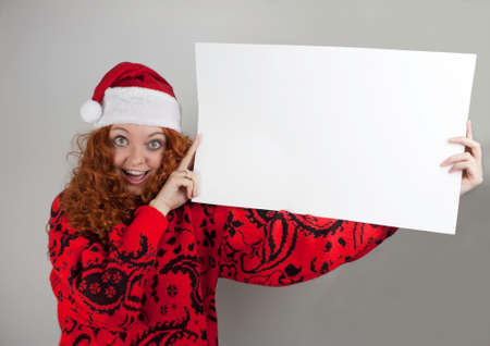 Pretty young woman wearing Santa hat and holding blank signの写真素材