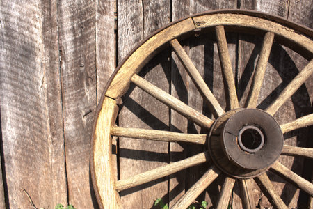 Wooden wagon wheel leaning against a weathered barnの写真素材