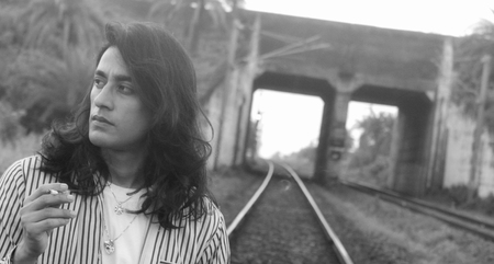 Long hair male smoking cigarette on railroad trackの写真素材