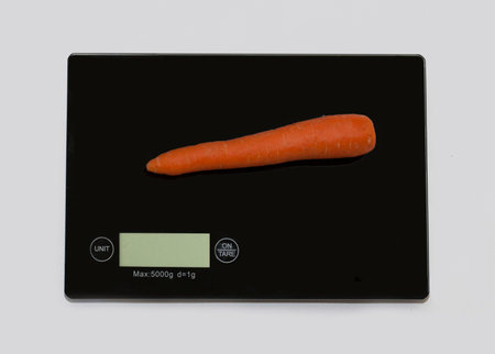 Carrot on a digital white kitchen scale. (weighing products)の写真素材