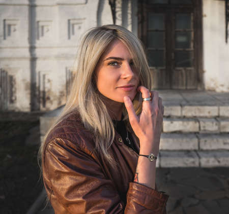Young blonde in brown leather jacket, hands at face. Fashion photoの写真素材