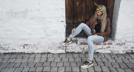 A girl is sitting on the background of an old doorの写真素材