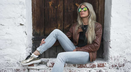 A girl is sitting on the background of an old doorの写真素材