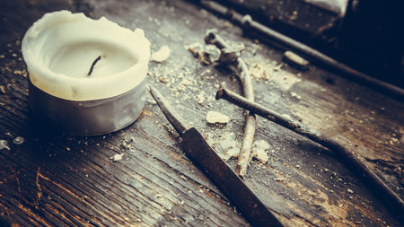 Rusty nails and a burnt candle on a wooden surfaceの写真素材
