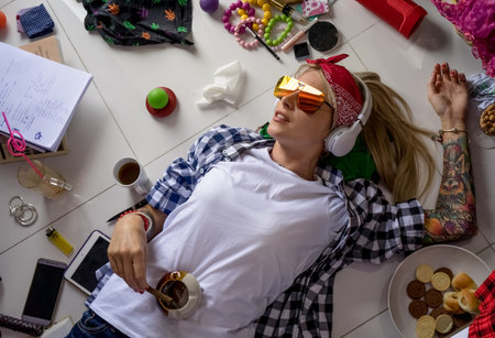 Young blonde woman lying on the floor with a cigarette in his hand and listens to music after school. Womens room, a mess, lingerie.の写真素材