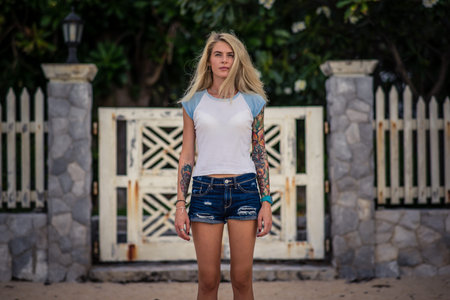 Summer portrait of a young stunning blonde girl. Wears a white tshirt and denim shorts. Outdoors, lifestyle, fashionの写真素材