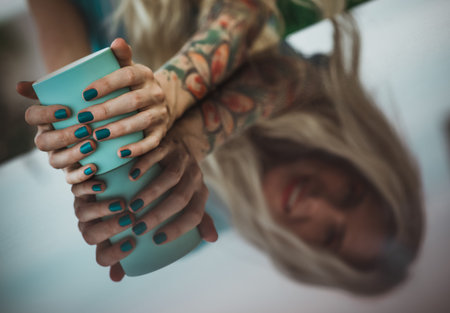 Female hands close up holding turquoise mug. The reflection on the table. dining in the open air,...