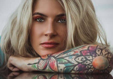 Closeup portrait of. Beautiful girl put her head in her arms with tattoos. expectation.の写真素材