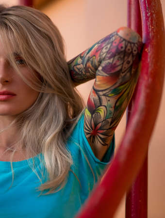 Beautiful blonde posing at the camera. Portrait on the background of bright orange wall. Modern hipster girl. Closeup portrait.の写真素材